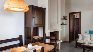 Un espace repas comprenant une table en bois, des chaises, un luminaire suspendu, un buffet et une cheminée.