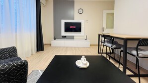 A modern living room with a flat-screen TV, a dining table with chairs, a sofa, and a coffee table. - One-Bedroom Apartment in Taksim - No: 5 (Istanbul)