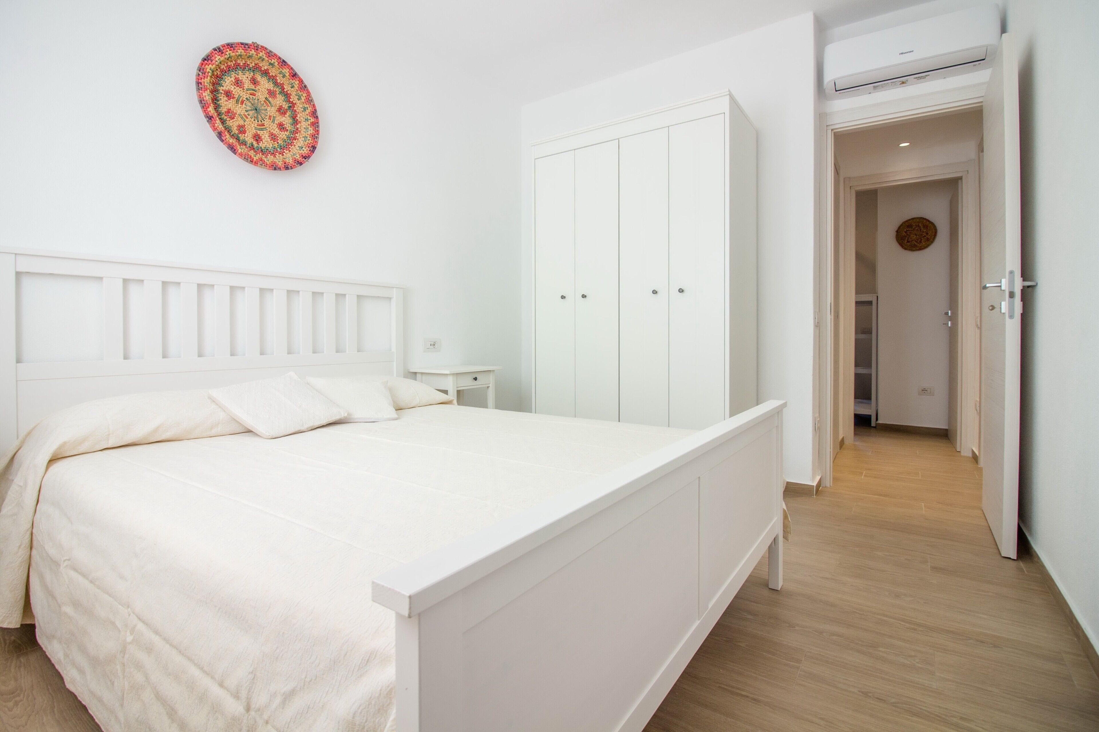 Ein Schlafzimmer mit einem Bett, einem Kleiderschrank, einem Nachttisch und einem Wanddekor.
