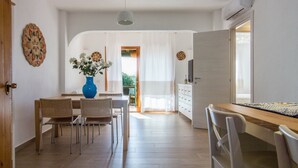 A dining area with a wooden table, chairs, a vase with flowers, and a white ceiling light. - Villa 'Porto Rotondo' with Sea View, Wi-Fi and Air Conditioning (Porto Rotondo)