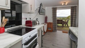 Una cocina moderna con estufa, horno y tostadora. Hay un comedor con mesa y sillas, y vistas al exterior.