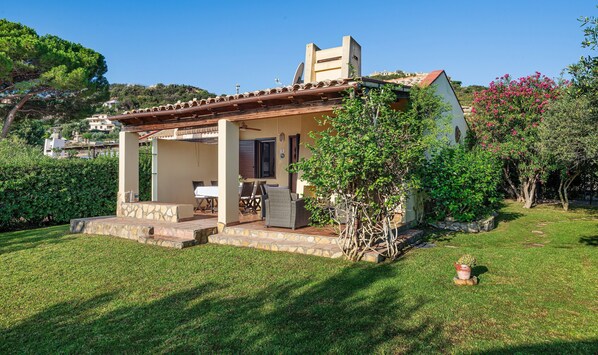 Une maison dotée d’un patio, d’un espace salon couvert et d’un jardin.