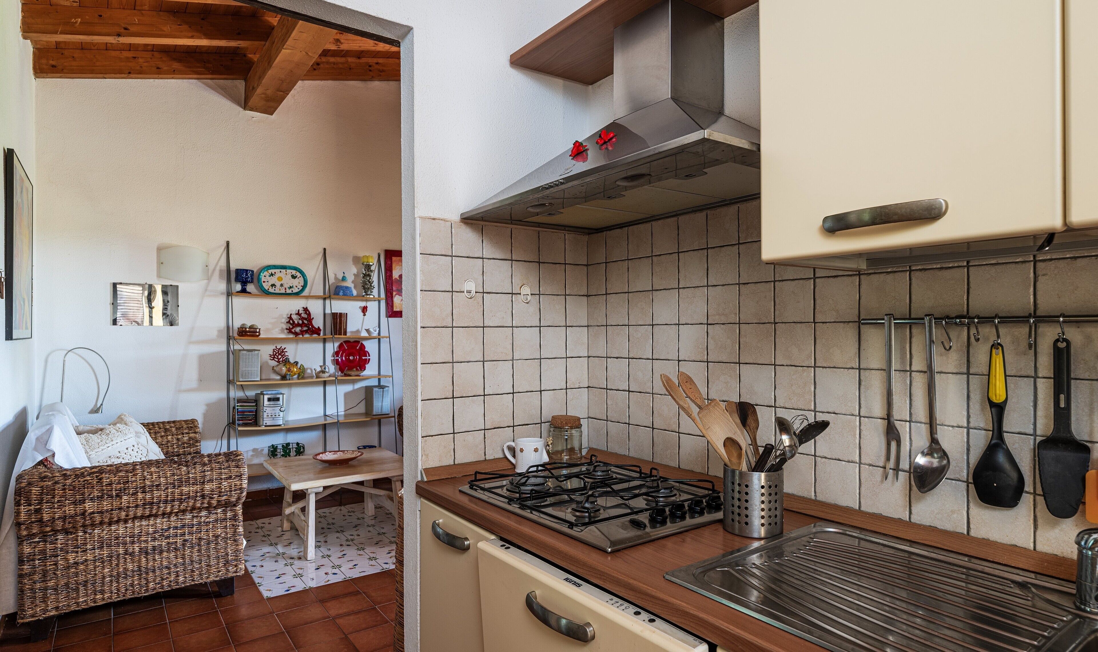 A kitchen with a gas stove, tiled backsplash, and hanging utensils.