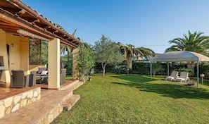 Un patio con mobiliario exterior, una zona de estar techada y un césped bien cuidado.
