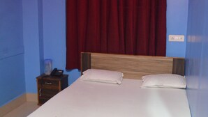 A bedroom with a bed, a nightstand, a red curtain, and a ceiling light fixture. - Hotel Dream Star  (Sahibganj)