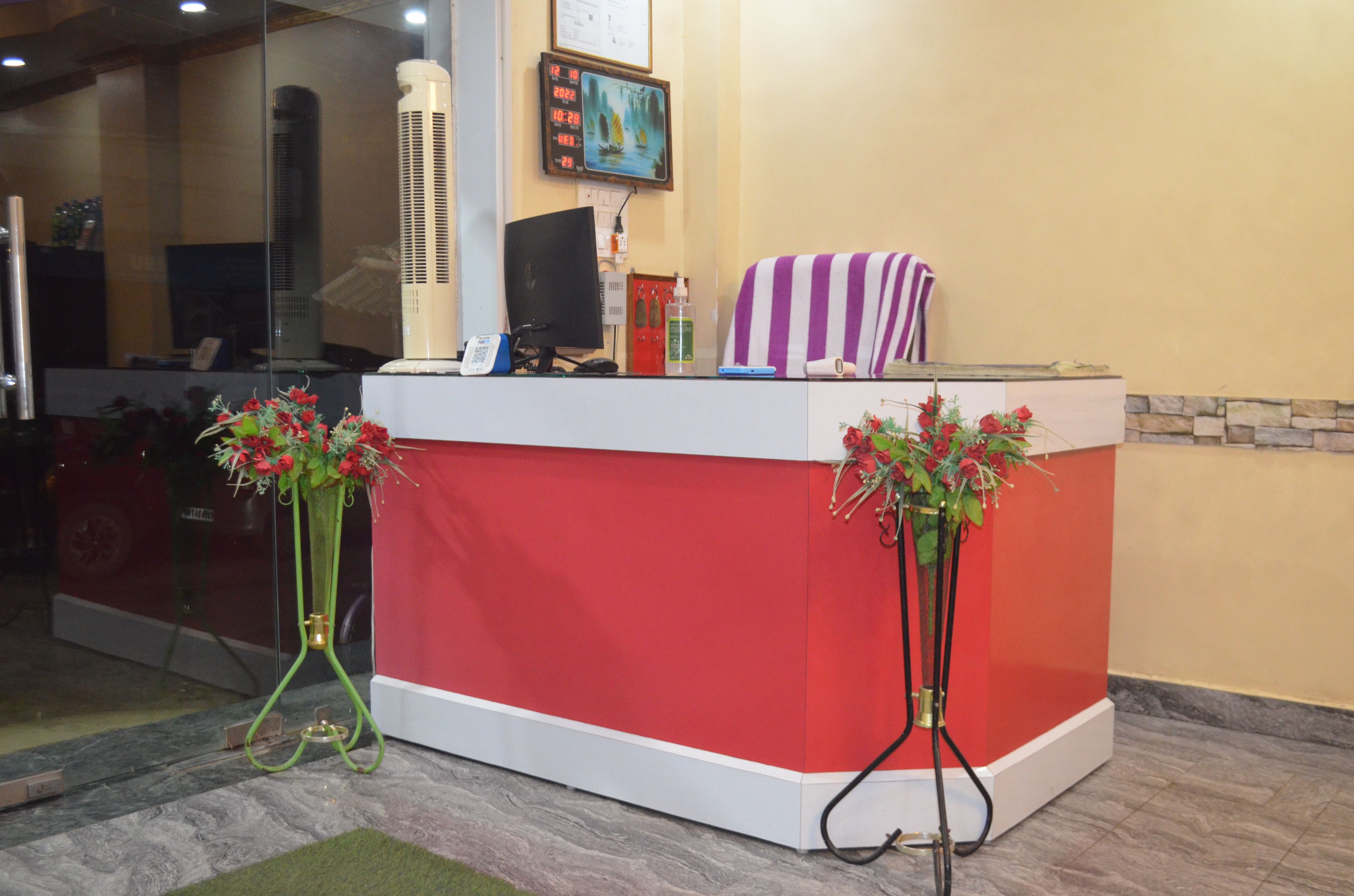 A reception desk with a red and white color scheme, a clock, and two flower arrangements on stands.