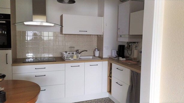 A modern kitchen with white cabinets, a wooden countertop, and a built-in oven. - T2 apartment 200 m from the sea (Concarneau)