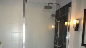 A bathroom with a glass-enclosed shower, a white sink, and a mirror with wall-mounted lights. - T2 apartment 200 m from the sea (Concarneau)