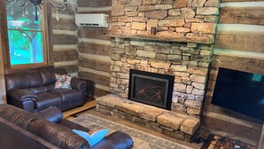 A log cabin interior with a stone fireplace, leather sofas, and a flat-screen TV. - Historic Cabin in the Blue Ridge Mountains (Pearisburg)