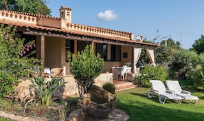 A house with a patio, outdoor seating, and a garden.
