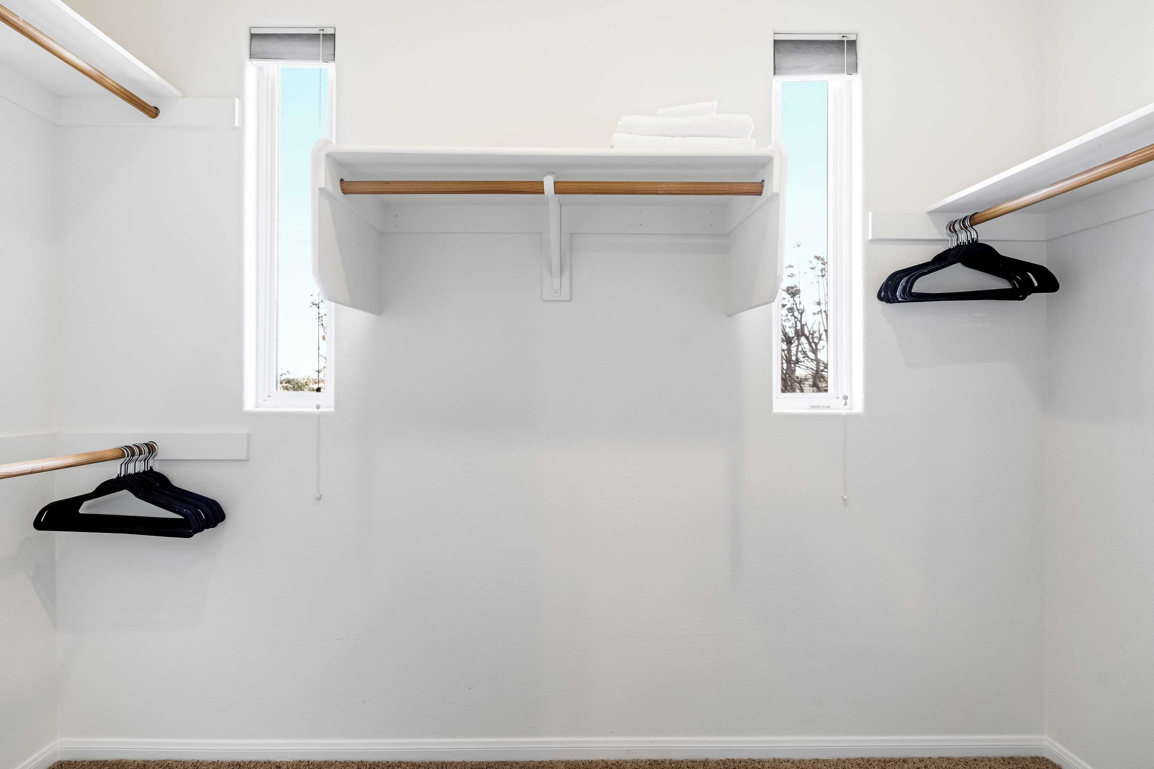 A room with a white wall, a wooden beam ceiling, and a window with a view.