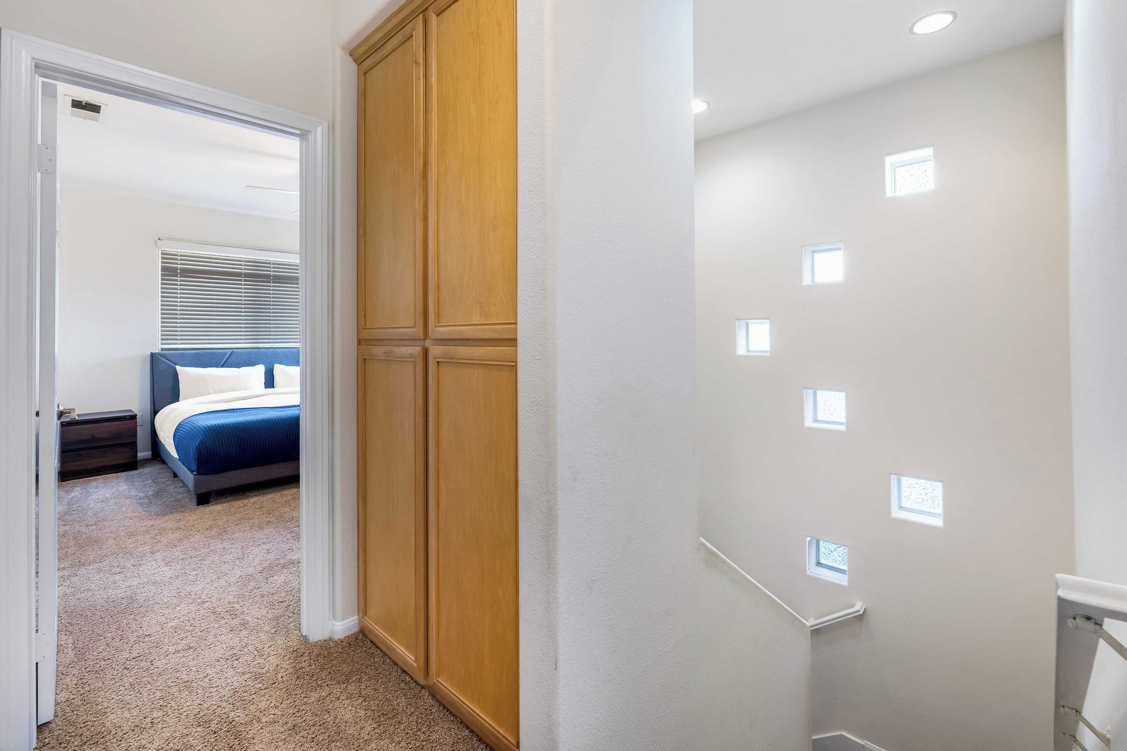 A bedroom with a bed, a wooden wardrobe, and a carpeted floor.