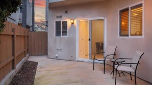 A patio with a wooden fence, a sliding glass door, and two chairs. - Walk to Dining, Mission + Pacific Beach, and Bars/nightlife Private Backyard (San Diego)