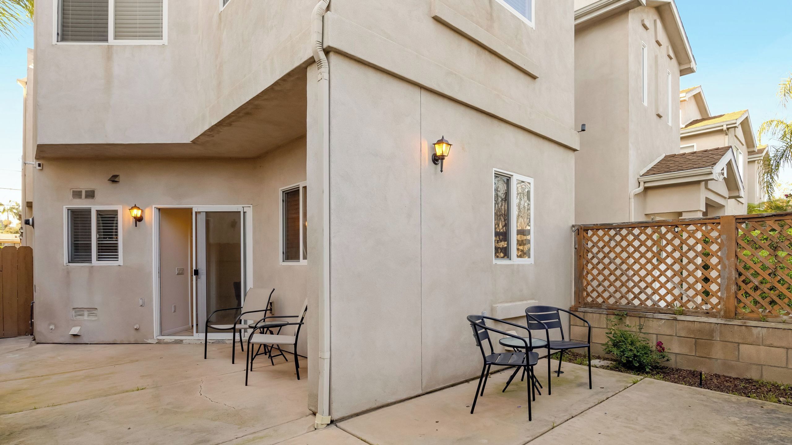 A two-story building with a patio area featuring outdoor furniture and a wooden fence.