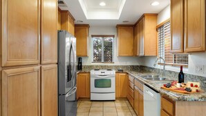 A kitchen with wooden cabinets, a stainless steel refrigerator, a white stove, and a granite countertop. - Walk to Dining, Mission + Pacific Beach, and Bars/nightlife Private Backyard (San Diego)