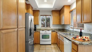 A kitchen with wooden cabinets, a stainless steel refrigerator, a white stove, a sink, and a window with blinds. - Walk to Dining, Mission + Pacific Beach, and Bars/nightlife Private Backyard (San Diego)