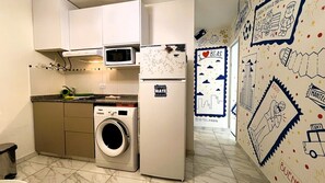 A compact kitchen with a washing machine, a microwave, and a refrigerator.