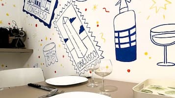 Comedor con una mesa dispuesta para dos personas, con un plato blanco, una copa de vino y cubiertos.