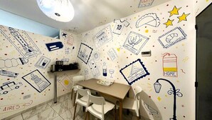 A room with a dining table, chairs, and a wall decorated with various doodles and text.