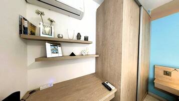 Habitación de hotel con un escritorio de madera, una estantería con objetos decorativos y vistas al exterior.