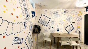Un espace repas comprenant une table, des chaises et un mur décoré de divers gribouillages et de textes.