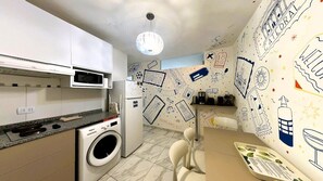 A modern kitchen with a washing machine, microwave, and a dining area with a table and chairs.