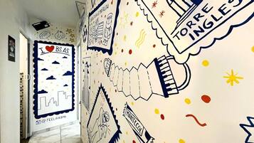Un pasillo con una pared decorada con varios dibujos y texto, incluyendo 'I ♥ BSAS' y 'TORRE INGLESO'.