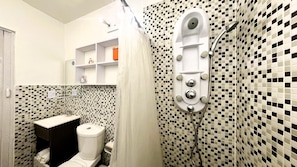 Une salle de bain comprenant des toilettes, une douche avec un panneau de commande et un mur carrelé.