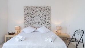 A neatly made bed with white linens, two bedside tables with lamps, and a decorative wall panel above the bed. - Villa 'Casa 1' with Sea View, Wi-Fi and Air Conditioning (Castiadas)