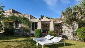 A stone villa with a garden, two white lounge chairs, and a pergola with red flowers. - Villa 'Casa 1' with Sea View, Wi-Fi and Air Conditioning (Castiadas)