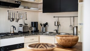 A kitchen with a gas stove, toaster, coffee maker, and various utensils on the wall. - Villa 'Casa 1' with Sea View, Wi-Fi and Air Conditioning (Castiadas)
