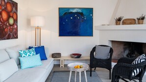 A living room with a sofa, a chair, a table with fruit, a fireplace, and two paintings. - Villa 'Casa 1' with Sea View, Wi-Fi and Air Conditioning (Castiadas)