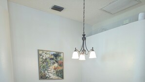 A dining room with a white table and chairs, a chandelier, and a painting on the wall. - The Garden House - 3BR /6 Guests (Lutz)