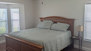 A bedroom with a wooden bed, a ceiling fan, and two windows with blinds. - The Garden House - 3BR /6 Guests (Lutz)