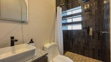 Un baño con un lavamanos blanco, un inodoro y una ducha con puerta de vidrio.