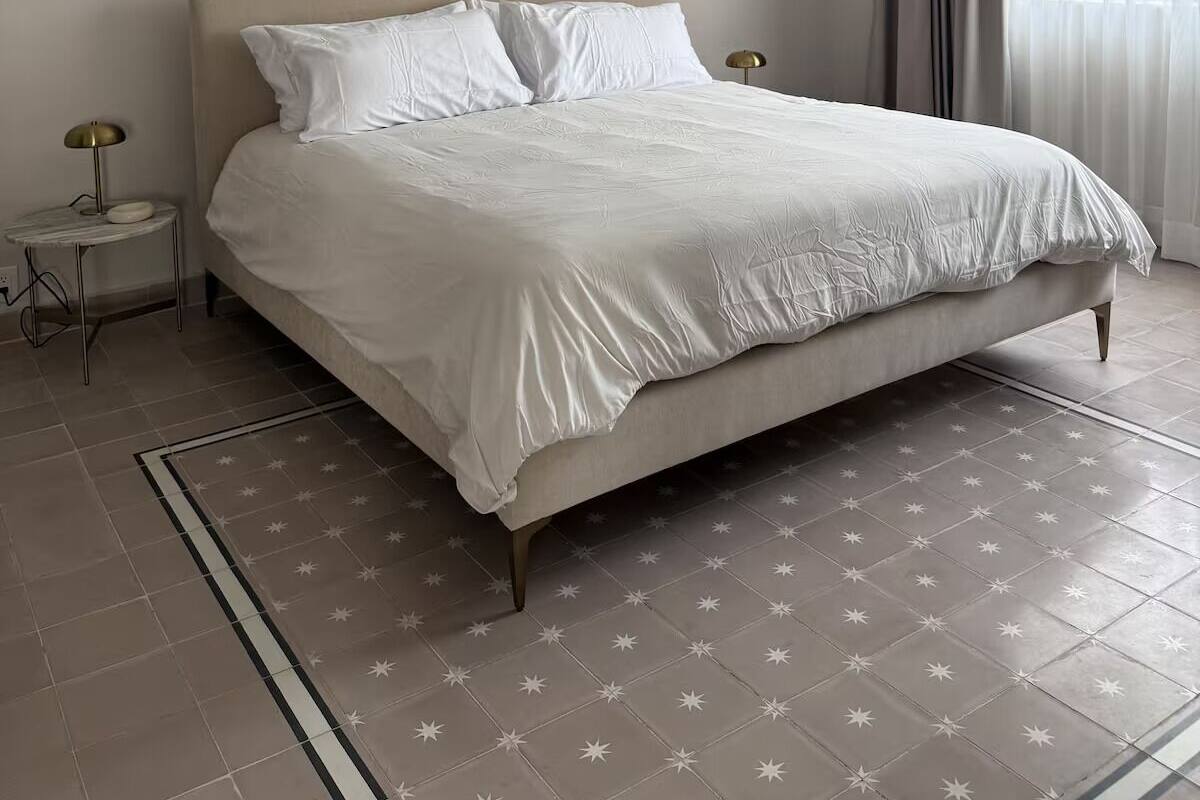 A minimalist bedroom with a large bed, a bedside table, and a nightstand.