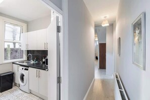 Eine moderne Küche mit weißen Schränken, einer integrierten Waschmaschine und einem Fenster.
