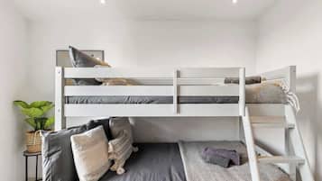 A bunk bed room with a small table, a potted plant, and a ladder.