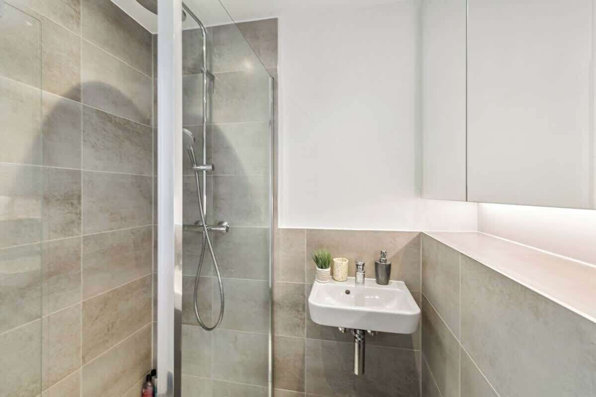 A modern bathroom with a shower, a sink, and a mirror.