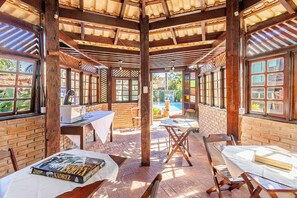 Un patio al aire libre con vigas de madera, paredes de ladrillo y varias mesas y sillas.