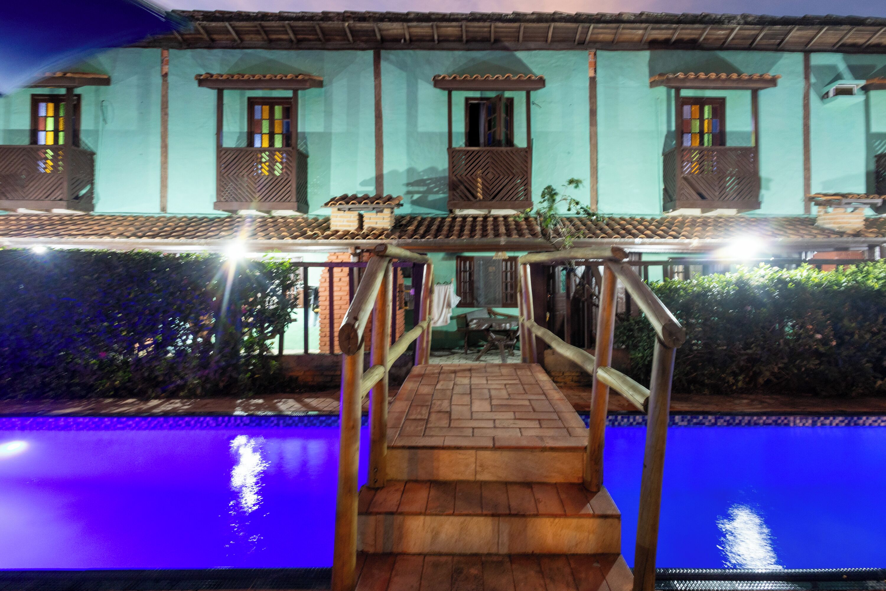 Un área de piscina con una escalera de madera que lleva a una terraza cubierta.