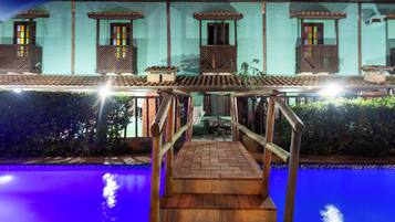 Un área de piscina con una escalera de madera que lleva a una terraza cubierta.