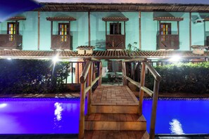 Un área de piscina con una escalera de madera que lleva a una terraza cubierta.