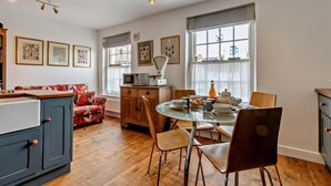 Una cocina acogedora con armarios de madera, una mesa de comedor con sillas y un sofá rojo con estampado floral.