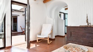 Una habitación con una silla de madera, una cesta tejida y un modelo decorativo de barco en un aparador.
