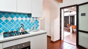 Una cocina con estufa a gas, hervidor y salpicadero de azulejos azules y blancos.