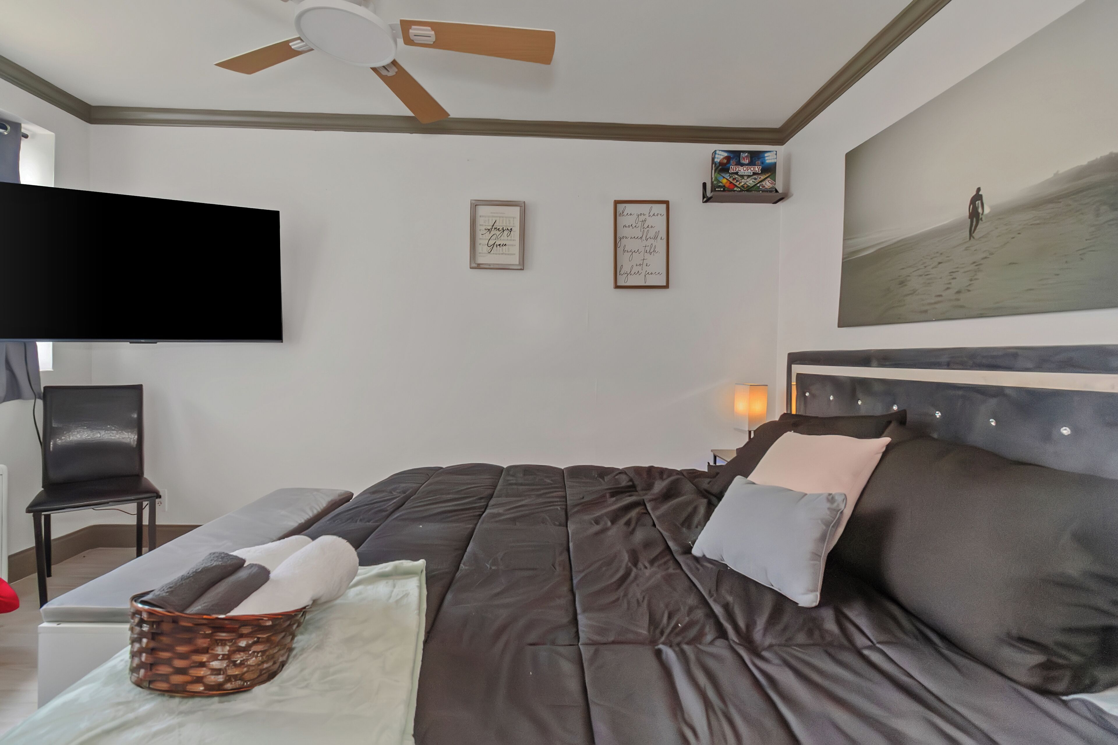 Une chambre dotée d’un grand lit, d’un téléviseur à écran plat, d’un ventilateur de plafond et d’un tableau encadré au mur.