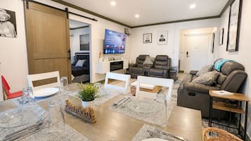 Un salon moderne comprenant un coin repas, un téléviseur, des canapés en cuir et une porte coulissante.