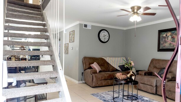 A staircase with a carpeted handrail, a brown sofa, a round coffee table, and a clock on the wall.