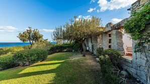 A stone building with a view of the sea, surrounded by greenery and trees. - Villa 'Casa 2' with Private Terrace, Garden, and Air Conditioning (Castiadas)